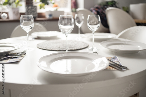 Empty glasses set in living room. Romantic table setting with white tablecloth, plates, crystal glasses. High quality photo