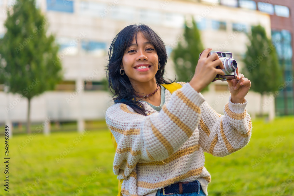 Portrait of a young Asian woman photographing with a vintage photo camera, backpacking traveler concept