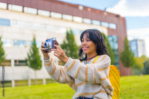 Asian young woman photography with a vintage photo camera visiting a city park, backpacker traveler concept