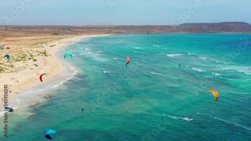 Kite surfers training in Sal, Cape Verde. 4K aerial drone view of coastline. Wavy ocean. Turquoise colorful ocean. Wide angle view. photo