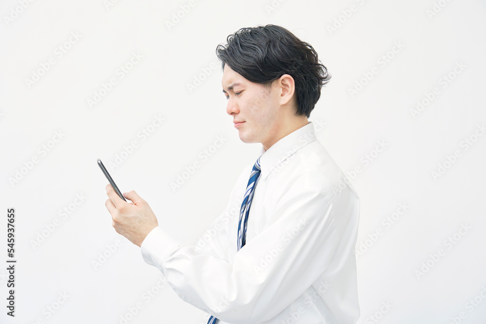 スマホを見て悩むビジネスマン 白背景 スマホを見て悩むビジネスマン 白背景