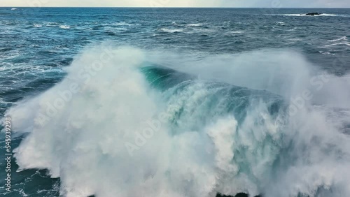 Flying over huge wave in atlantic ocean. Aerial filming breaking surf with foam. Powerful stormy sea or ocean waves