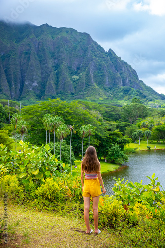 beautiful girl walks through Ho'omaluhia Botanical Garden admiring the mighty mountains on oahu, hawaiian islands; holiday in hawaii