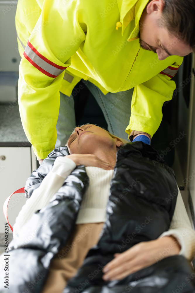 Paramedic in uniform giving first aid to middle aged patient in emergency vehicle. Paramedic in uniform giving first aid to middle aged patient in emergency vehicle.