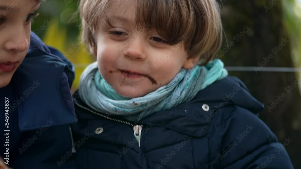 Small boy eating belgium street food outside during winter season. Children wearing coat snacking sweet dessert Small boy eating belgium street food outside during winter season. Children wearing coat snacking sweet dessert