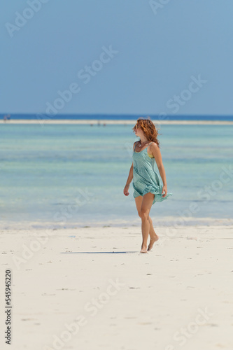 Young pretty woman on the tropical sandy beach with turquoise water sea background, Zanzibar 