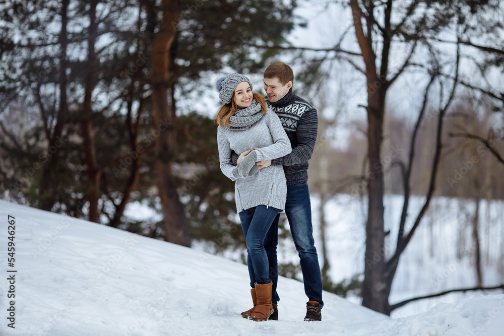 The couple hugs and smiles while standing in the snow.