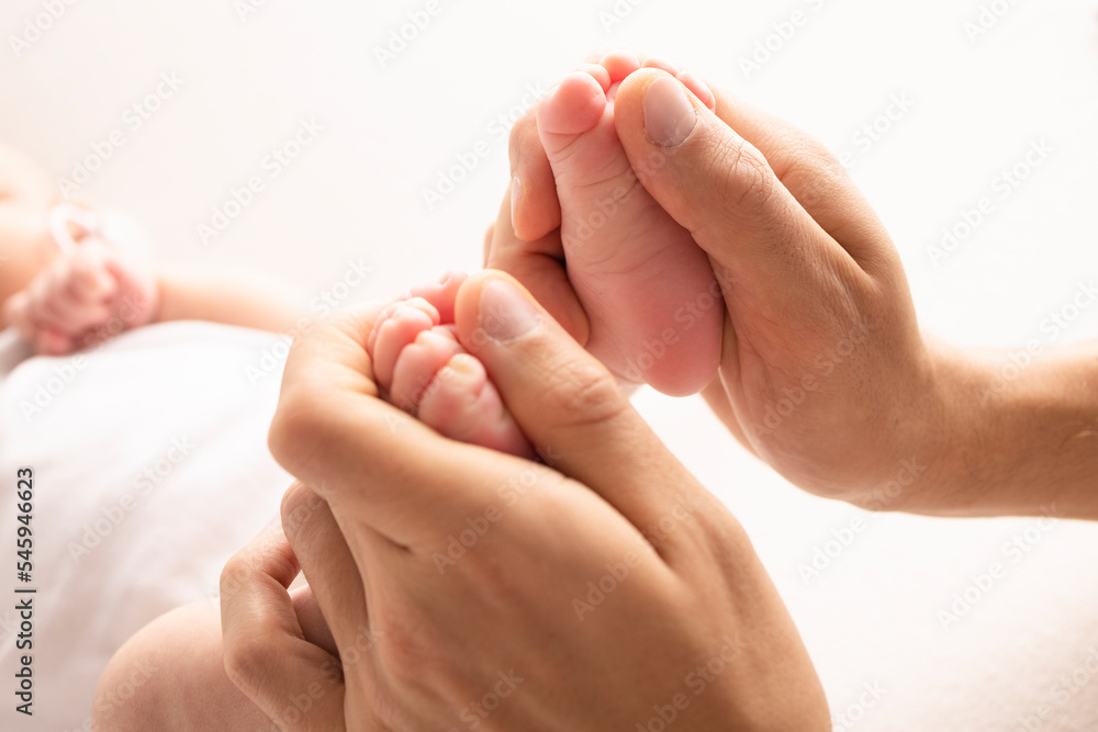 Mother is doing massage on her baby foot. Close up baby feet in mother hands on a white background. Prevention of flat feet, development, muscle tone, dysplasia. Family, love, care, and health concept Mother is doing massage on her baby foot. Close up baby feet in mother hands on a white background. Prevention of flat feet, development, muscle tone, dysplasia. Family, love, care, and health concept