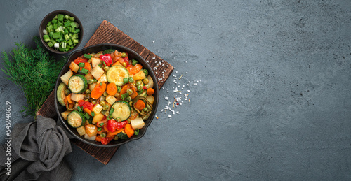Vegetable stew with fresh herbs on a dark background. Vegetarian food. Top view, copy space.