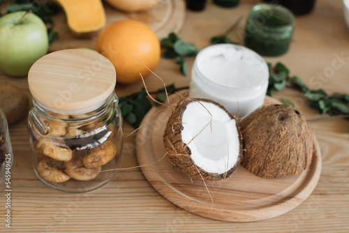 Various ingredients lying at wooden table for preparing natural cosmetics at home. Coconut, orange, mint, fig skin and hair care home spa. Jar of mask and cream.