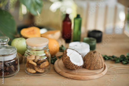 Various ingredients lying at wooden table for preparing natural cosmetics at home. Coconut, orange, mint, fig skin and hair care home spa. Jar of mask and cream.