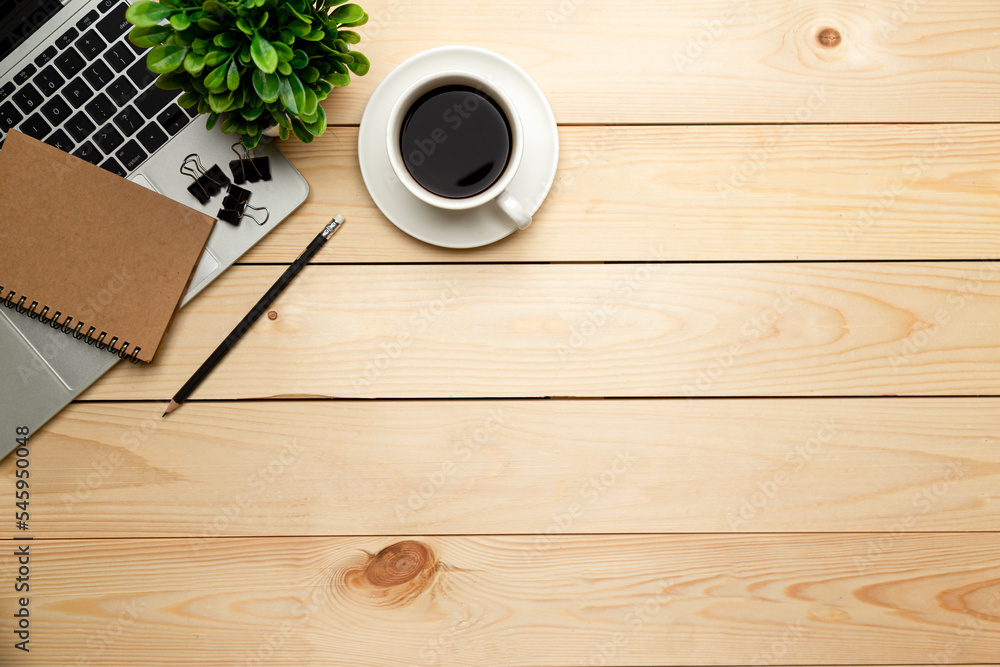 Top view office table desk. Workspace with blank, office supplies,Laptop, pencil, green leaf, and coffee cup on wood background. Top view office table desk. Workspace with blank, office supplies,Laptop, pencil, green leaf, and coffee cup on wood background.