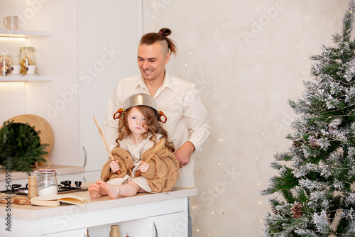 Family - father and daughter, happy together at home in the kitchen preparing Christmas dinner at the Christmas tree