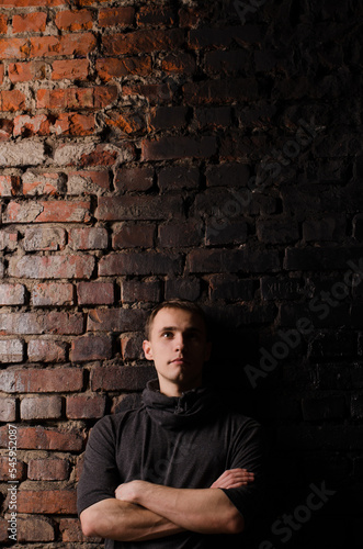 young man in a black jacket against the background of a brown, red and black brick wall