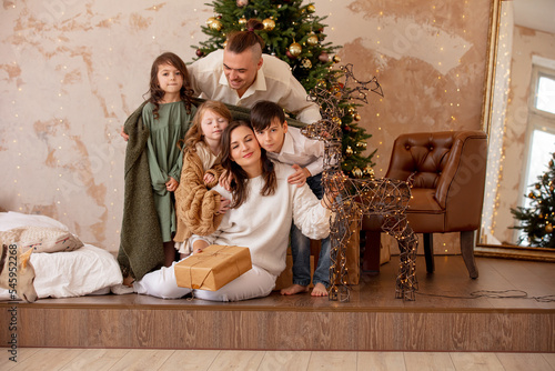 Family - father, mother and three children, happy together at home celebrating Christmas at a decorated Christmas tree © kuzmichstudio
