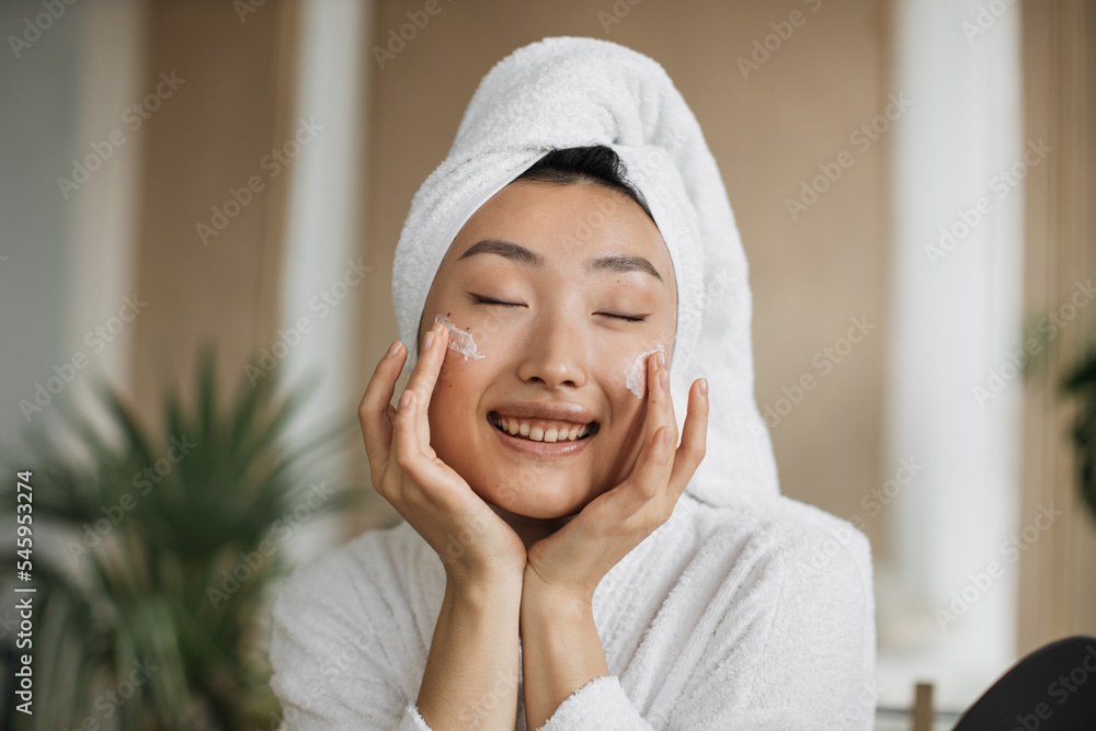 Close up view of face of young asian woman applying natural cosmetics at home, making homemade cream for skin, hair care at with exotic background in spa resort Close up view of face of young asian woman applying natural cosmetics at home, making homemade cream for skin, hair care at with exotic background in spa resort