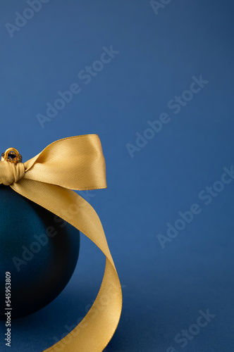 Blue Christmas bauble decoration with yellow ribbon. Minimal New Year concept.