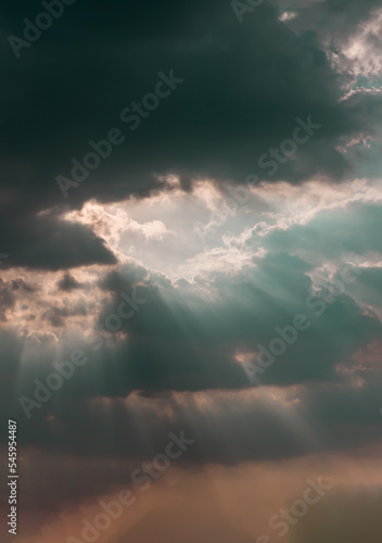 The sun's rays passing through the clouds and shining form an interesting light pattern against the sky. Space for text, Selective focus. © num