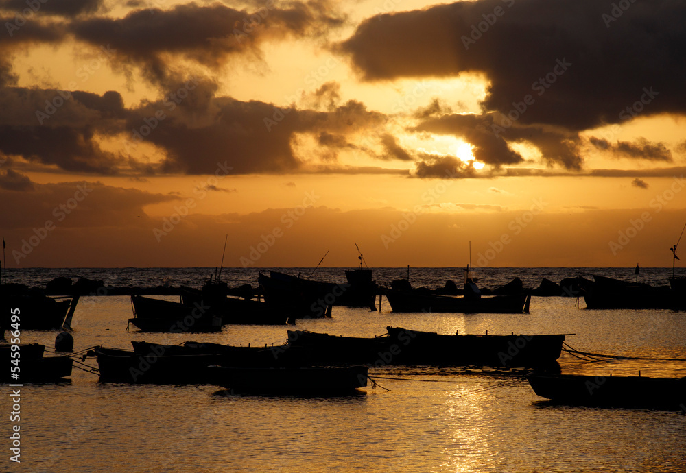 Silhouette many fishing ships in harbor on seaside with altostratus clouds in colorful sunrise sky background and reflection on sea surface at morning time