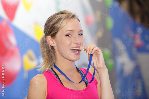 female athlete biting gold medal photo
