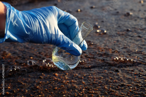 Hand in glove holding water sample for analiysis, with sunlight. Ecology concept. Copy space