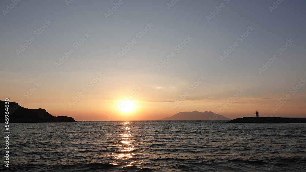 Sea port view, lighthouse, mountains and the opposite island of Samothrace in Gökçeada, Imbros Island at sunset