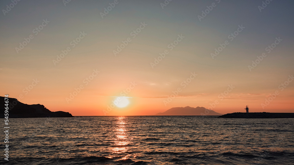 Sea port view, lighthouse, mountains and the opposite island of Samothrace in Gökçeada, Imbros Island at sunset Sea port view, lighthouse, mountains and the opposite island of Samothrace in Gökçeada, Imbros Island at sunset