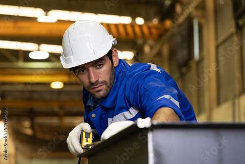 Focused construction worker using measuring tape to complete a metalworking project on the factory floor