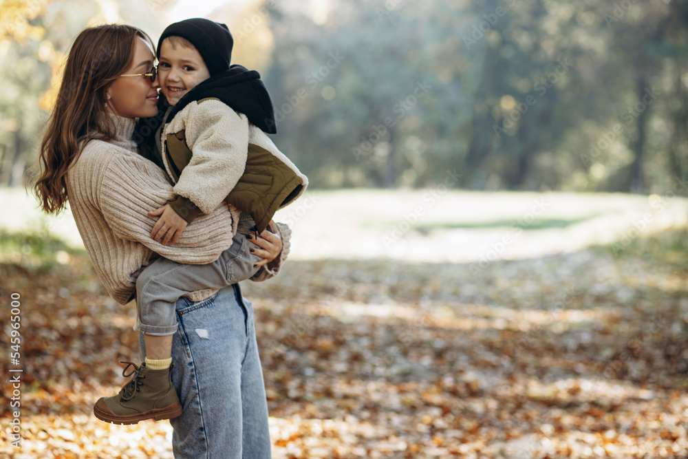 Mother with her little son walking in autumnal park Mother with her little son walking in autumnal park