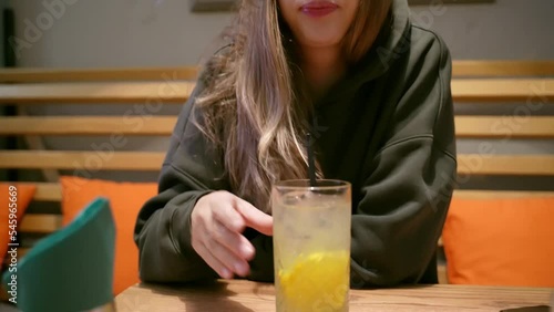 Young woman drinking lemonade with a cocktails tube in the restaurant