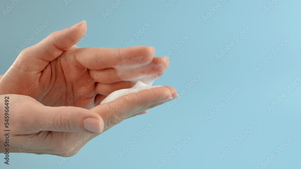 Young woman washing her hands with soapy foam on blue background. Concept of hand washing, hygiene, health, virus and bacteria protect. Using an automatic soap dispenser. White foam soap Young woman washing her hands with soapy foam on blue background. Concept of hand washing, hygiene, health, virus and bacteria protect. Using an automatic soap dispenser. White foam soap