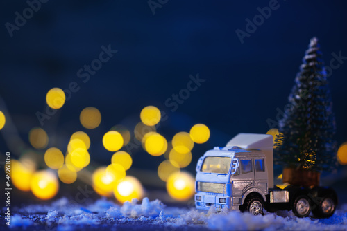Toy truck transports Christmas tree, festive background, bokeh garlands