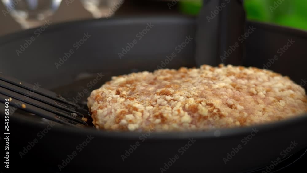 Kitchen tongs turn fried chicken schnitzel in sizzling oil in hot frying pan. Chicken meat is fried on stove. Food concept Kitchen tongs turn fried chicken schnitzel in sizzling oil in hot frying pan. Chicken meat is fried on stove. Food concept