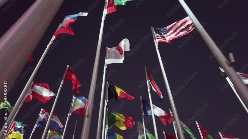Flags of the different countries wave in slow motion against dark night ...