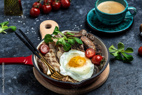 Baked sweet purple potatoes, grilled bacon and fried egg in pan and coffee on white background. Keto breakfast or lunch. Healthy fats, clean eating for weight loss, top view