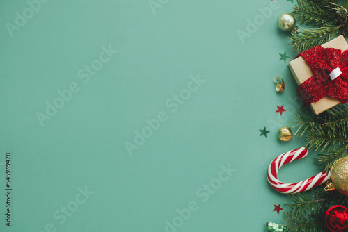Merry Christmas  Stylish christmas border with festive decorations  confetti gift  fir branches on green background. Christmas flat lay. Seasons greetings card template  space for text