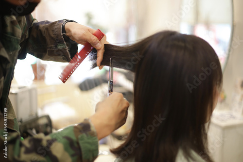 女性の髪を切る男性美容師