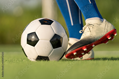 Athlete standing with ball on football field during sunrise, soccer ball in net on sky background, ball movement, popular sports on football club, World cup.