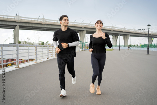 Sports weekends, use fitness watches. A woman and a man are running and doing sports on the street.