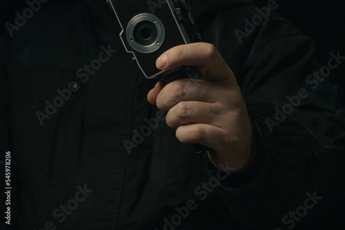 Vintage movie camera in man hand isolated on a blackbackground