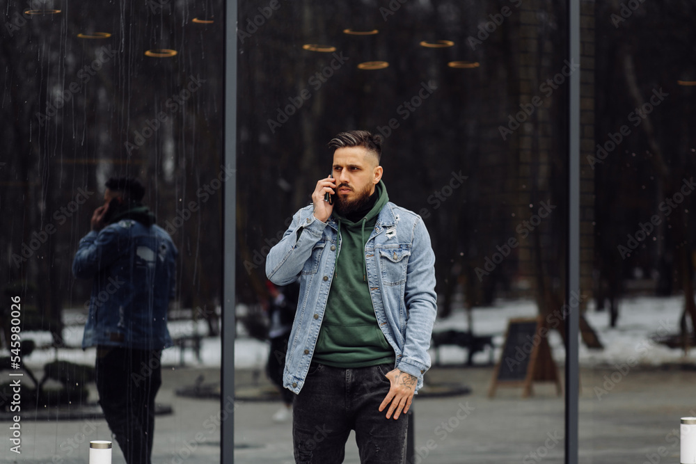 Young dark-haired caucasian man holding his cell phone in the street Young dark-haired caucasian man holding his cell phone in the street