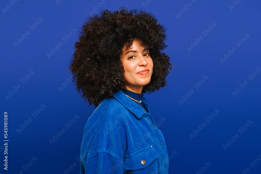 Portrait of a happy young woman standing against a blue background Portrait of a happy young woman standing against a blue background