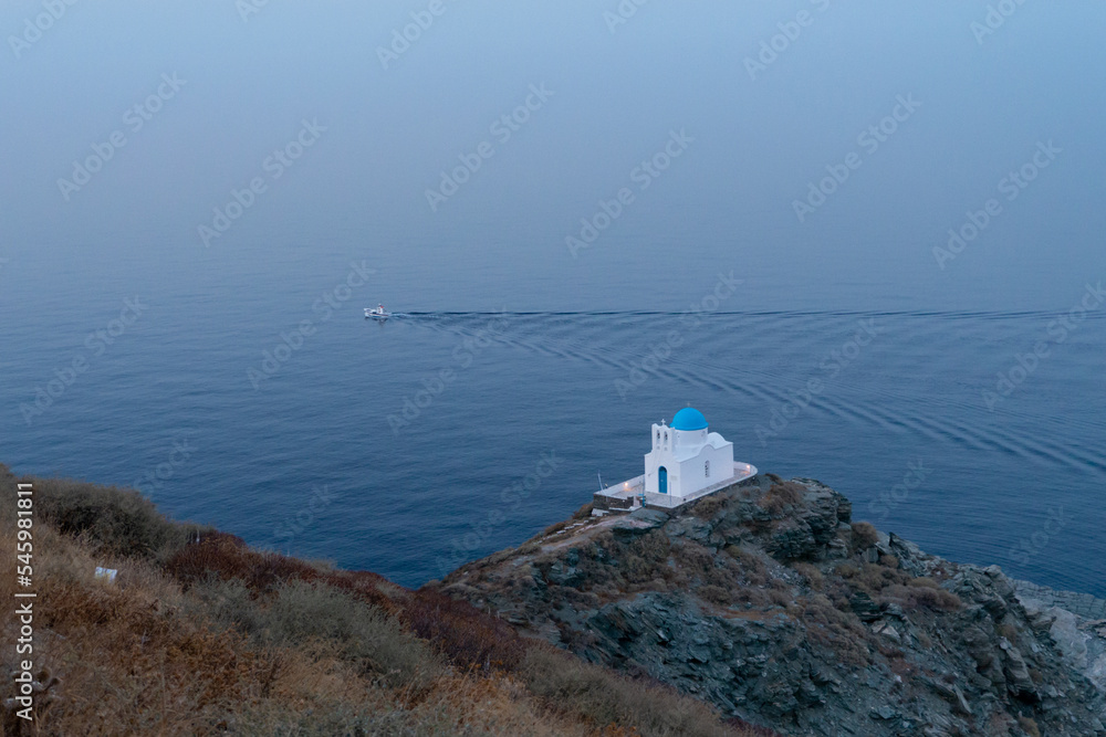 Petite chapelle face à la mer avec bateau de pêche traçant un sillon à proximité