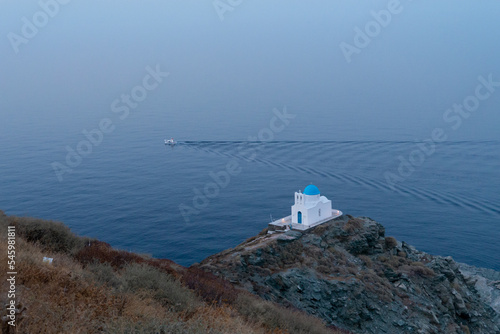 Petite chapelle face à la mer avec bateau de pêche traçant un sillon à proximité