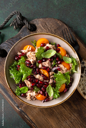 bowl with salad with tuna, tomatoes and pomegranate on the table