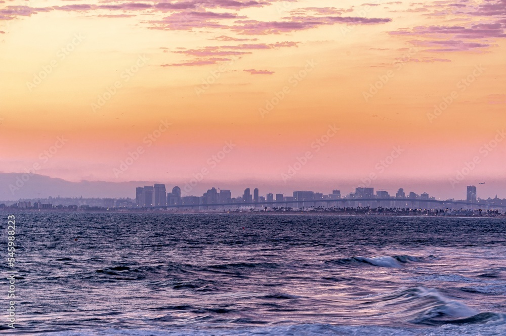 Panoramic shot of the sea and colorful sunset over the cityscape at the horizon