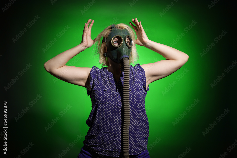 shocked woman in gas mask holding her head on dark background