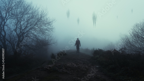 A man looking up at mysterious floating figures in the sky. On a spooky foggy, winters day in the countryside.