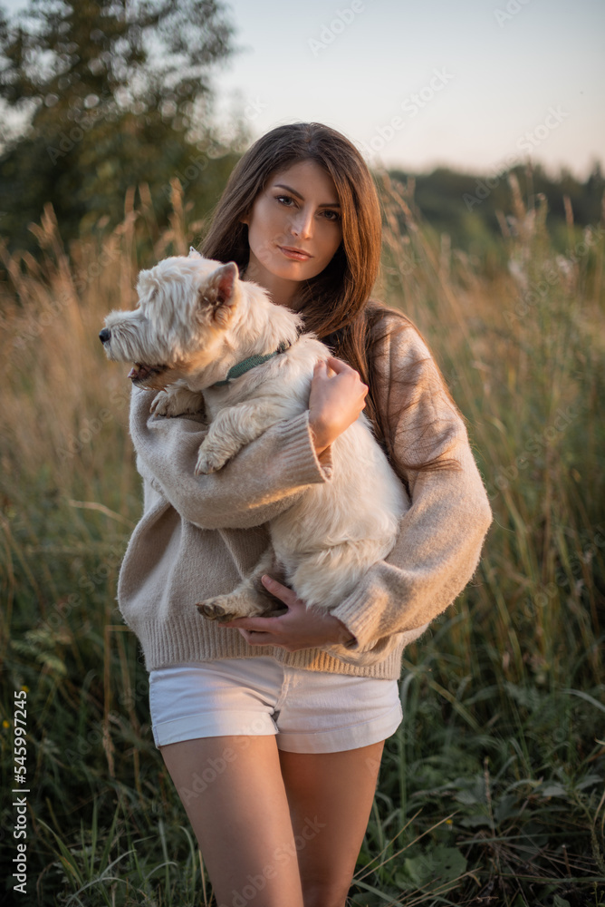 portrait of a beautiful young girl with a dog in her arms, a girl hugs her beloved petam on a walk, West Highland White Terrier,vertical portrait, copy space portrait of a beautiful young girl with a dog in her arms, a girl hugs her beloved petam on a walk, West Highland White Terrier,vertical portrait, copy space