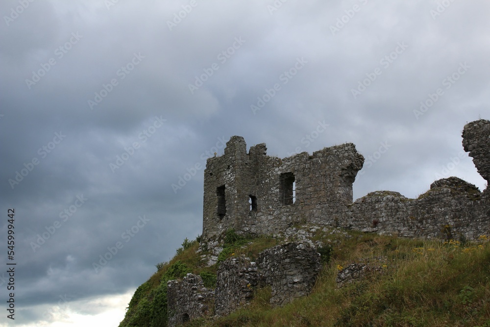 Low angle shot of Rock of Dunamase on a green hill against a cloudy sky in Ireland
